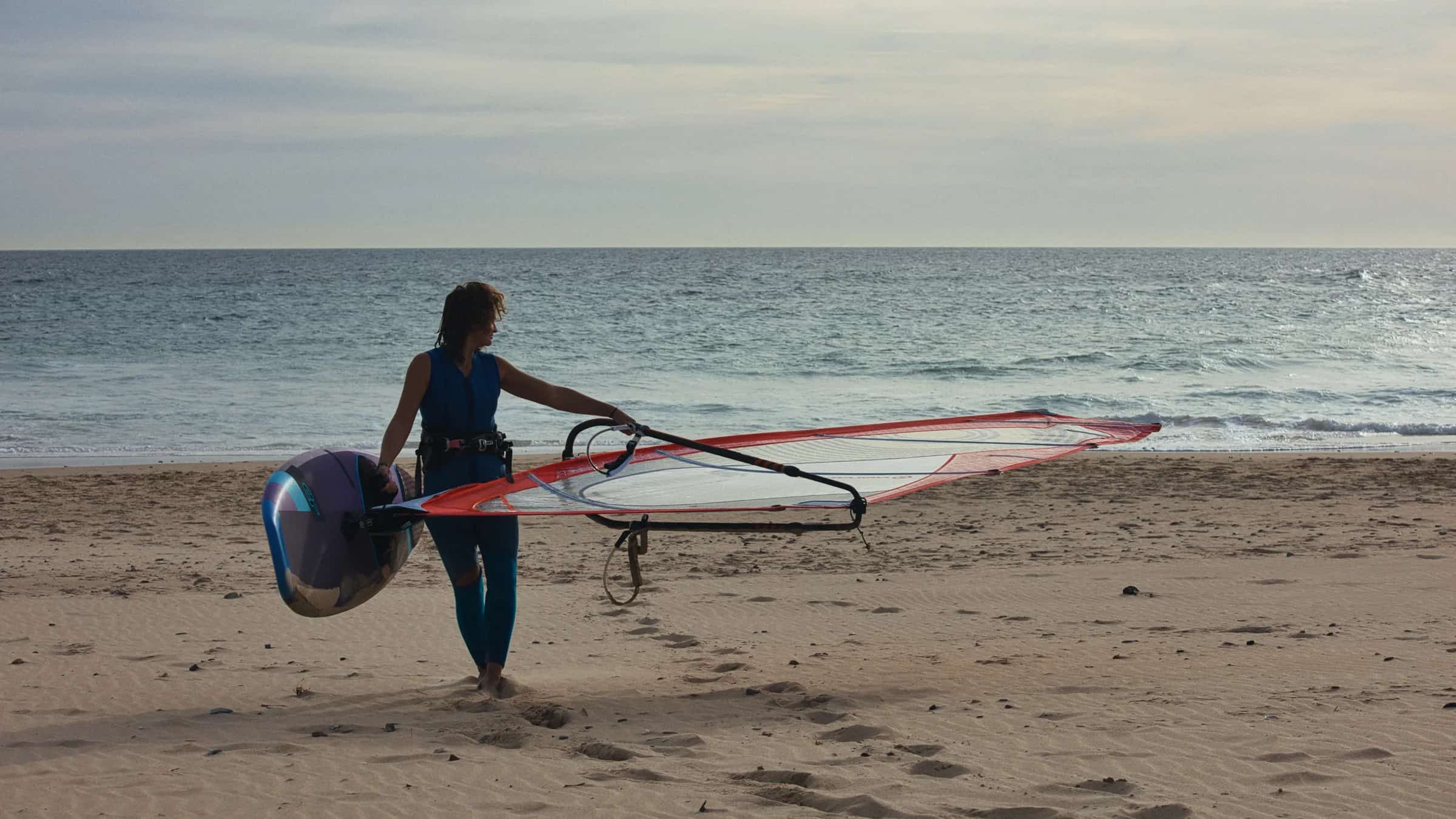 A windsurfer preparing with equipment on the beach