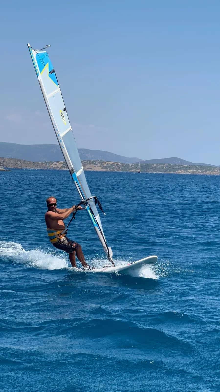Rüzgârlı koşullarda hızlı ve kontrollü windsurf yapan sporcu