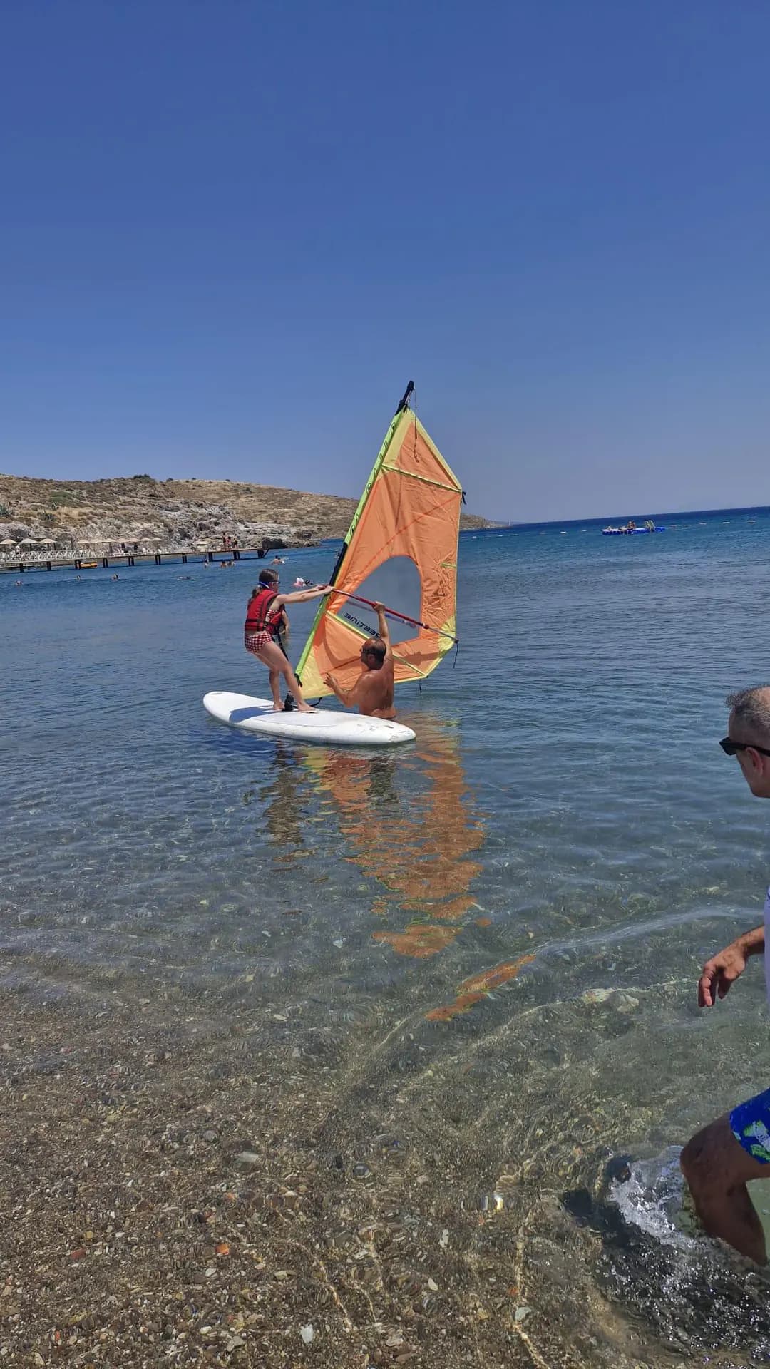 Participant and instructor working beside a sailboard on the Bodrum shore