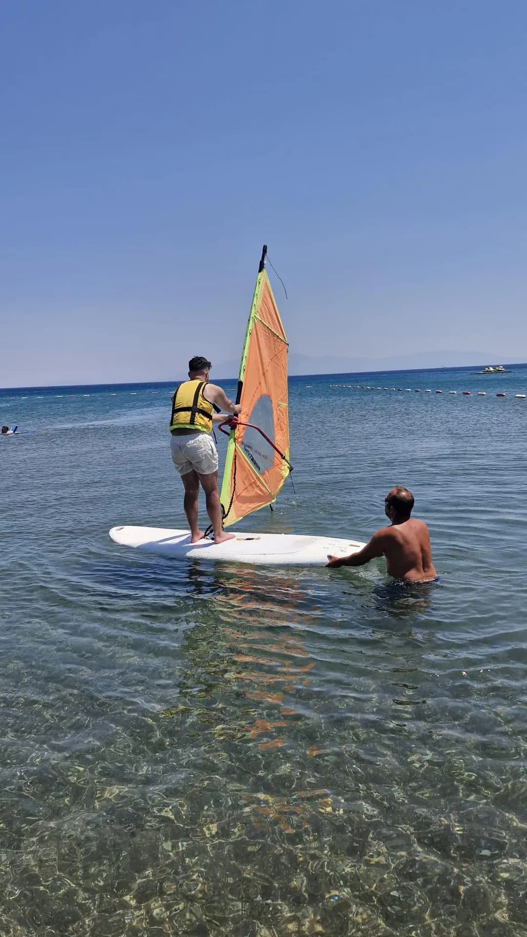 Instructor steadying the board for a participant wearing a buoyancy aid