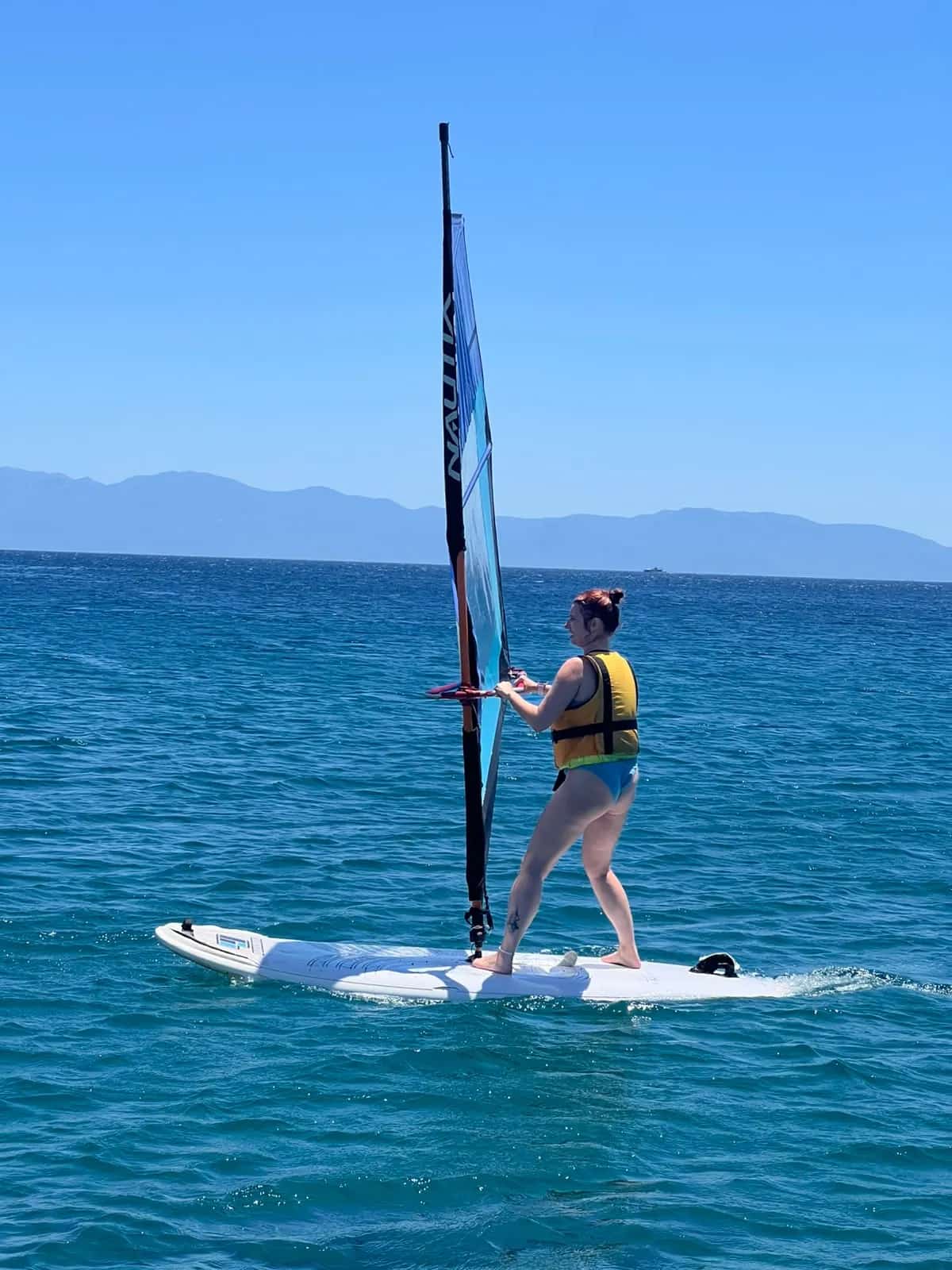 Sığ suda tek başına denge çalışan windsurf katılımcısı